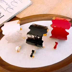 Détail d'un ensemble de bijoux en émail avec des bracelets et bagues géométriques irréguliers.