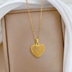 Close-up of gold hollow heart pendant necklace with intricate mesh texture detail.