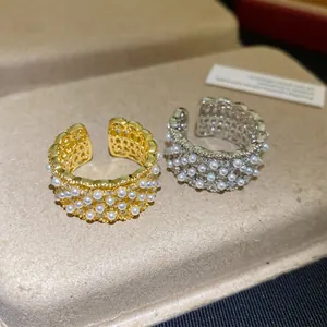 Macrodetail van 18k vergulde opengewerkte ringen met kleine parels en sprankelende zirkoon