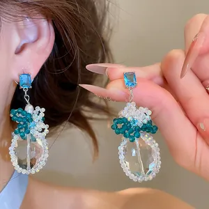 Detailopname van elegante blauwe zirkoon en kristallen kralen hangende oorbellen