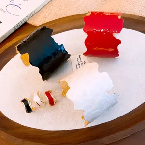 Gros plan de joncs et bagues en émail géométrique irrégulier en noir, rouge et blanc.