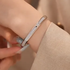 Detailed view of an 18K gold plated oval bangle paved with cubic zirconia on a model's wrist