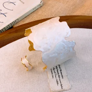 Gros plan sur un ensemble de bracelet manchette et de bague en émail blanc et doré