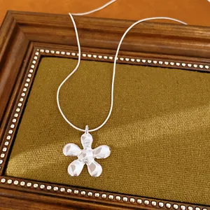 Detailweergave van een gepolijste zilveren bloemenhanger aan een slangenketting.