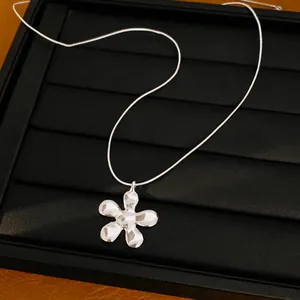 Detailopname van een zilveren ketting met vijfbladige bloemenhanger met textuur