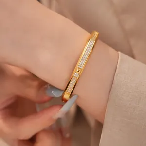 Detailed view of luxury 18K gold-plated zirconia bangle bracelet worn on a woman's wrist