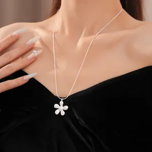 Gedetailleerd zicht van een zilveren bloemenhanger ketting op een model in zwart fluweel.