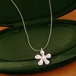 Detailopname van een gepolijste zilveren bloemhanger ketting in een groene fluwelen doos