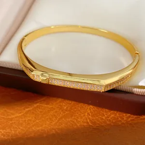 Close-up of 18K gold plated bangle featuring sparkling zircon stones and oval buckle design.