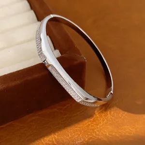 Detail shot of a minimalist 18K gold plated oval bangle inlaid with sparkling white zircons