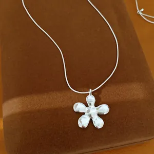 Detailopname van een gepolijste zilveren bloemenketting op een bruine fluwelen stand