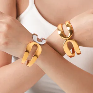 Detailopname van minimalistische 18k vergulde holle manchetarmband om de pols van model
