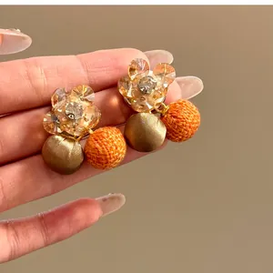 Detailopname van zirkoon bloemoorbellen met bronzen zijde en oranje geweven bollen