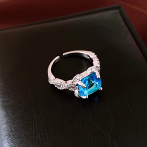 Close-up of luxury silver-toned open ring featuring a square blue zircon and pavé accents.