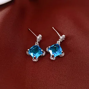 Elegant French court style square blue zircon stud earrings on red silk background.