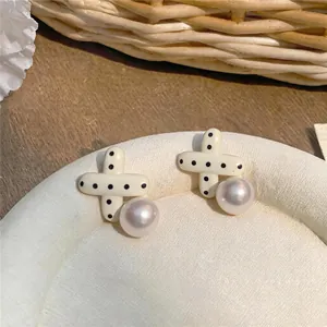Primo piano di eleganti orecchini a perno con croce a pois e perni in argento puro