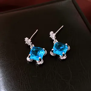 Macro view showing the fine detail of square blue zircon stud earrings with crystal accents