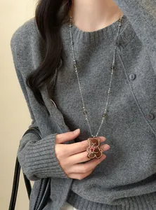 Gros plan d'un collier pendentif ours brun avec des perles de verre sur un cardigan gris