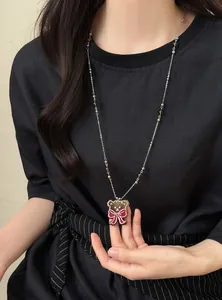 Gros plan d'un collier rétro en perles de verre avec un pendentif ours et nœud rouge.