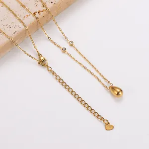 Detail van gouden roestvrijstalen ketting met waterdruppel hanger en CZ accenten