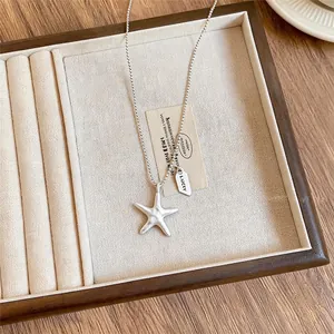 Detailopname van een zilveren zeester hanger ketting met LUCKY tag in sieradendoos
