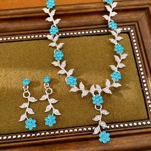 Detailaufnahme von Halskette und Ohrringen mit blauen Strassblüten und Blättern auf Display.