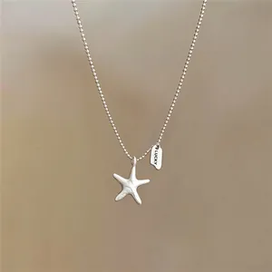 Detailopname van een zilveren zeester hanger ketting met een gegraveerd Lucky label