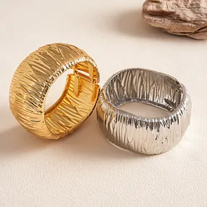 Detailed view of gold and silver metallic bangles with vertical pleated texture