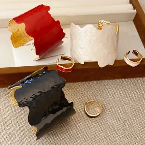 Detailansicht von unregelmäßigen Emaille-Armreifen und passenden Ringen in Rot, Weiß, Schwarz.