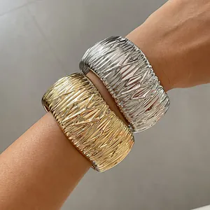 Close-up of pleated texture metal bangles in gold and silver finish worn on wrist