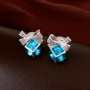 Clip d'oreilles argenté élégant avec un nœud en zircon scintillant et un cristal bleu cubique