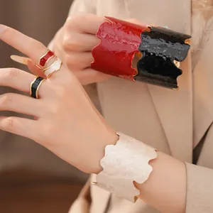Detailansicht farbenfroher Emaille-Ringe und breiter Manschetten mit Wellenrand.