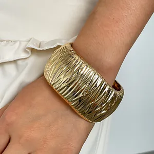 Detailed view of a wide gold metal bangle with stylish crinkled texture for women