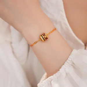 Detail of a 24K gold-plated bracelet with a zircon flower charm on a lady's wrist
