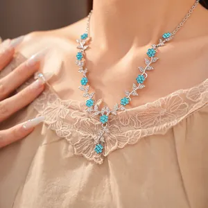 Elegante silberfarbene Halskette mit blauen Strassblumen und Blattmotiven am Modell