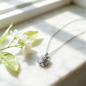 Gedetailleerde opname van een roestvrijstalen uilenhanger ketting met zilveren finish