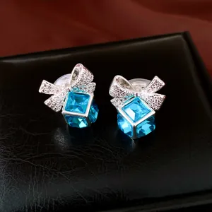 Gros plan d'élégantes boucles d'oreilles clip carrées en cristal bleu avec nœud argenté