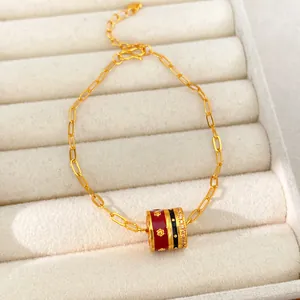 Close-up of gold-plated bracelet with red and black enamel charm and zircons on velvet