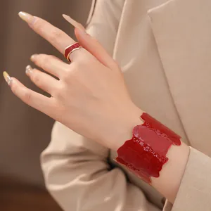 Detailansicht eines roten Emaille-Armreifs und passenden Rings an der Hand eines Models