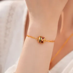 Close-up of gold plated bracelet with red and black enamel flower charm and zircons