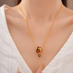 Close-up of 24K gold plated necklace with enamel floral cylinder pendant.