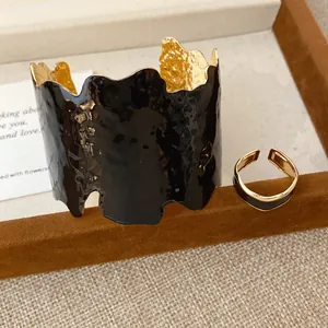 Detail von unregelmäßigem schwarzen Emaille- und Gold-Armreif mit passendem Ring
