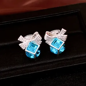 Gros plan sur les boucles d'oreilles nœud avec zircon bleu et pierres pavées.
