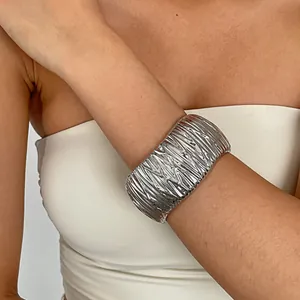 Close-up detail of a silver metallic crumpled texture cuff bracelet worn on the wrist