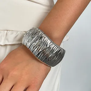 Close-up of a silver wrinkled metal cuff bracelet with a unique geometric texture design