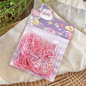 Close-up of pink disposable elastic hair bands in cute purple cartoon packaging.