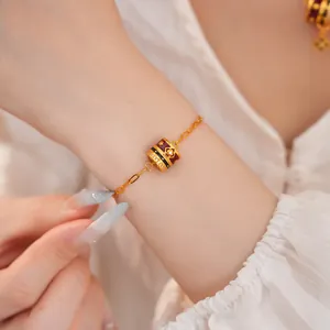 Detailed view of a 24K gold plated bracelet with a zircon-set enamel flower charm.