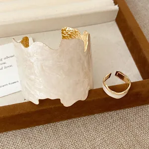 Elegantes Set aus unregelmäßigem Manschettenarmband und passendem Goldring in Cremeweiß