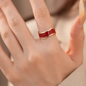 Detailaufnahme eines roten Emaille-Rings mit unregelmäßigen goldenen Wellenkanten
