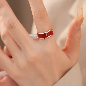 Makroansicht eines unregelmäßigen wellenförmigen Rings mit roter Emaille und Goldfinish.